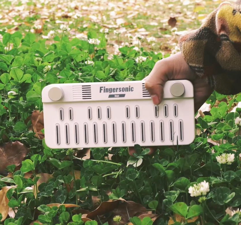 Fingersonic Keys portable MIDI keyboard shown outdoors in hand, highlighting its compact design for music creation on the go